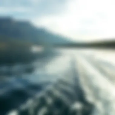 A calm lake with a wake surf boat in the distance